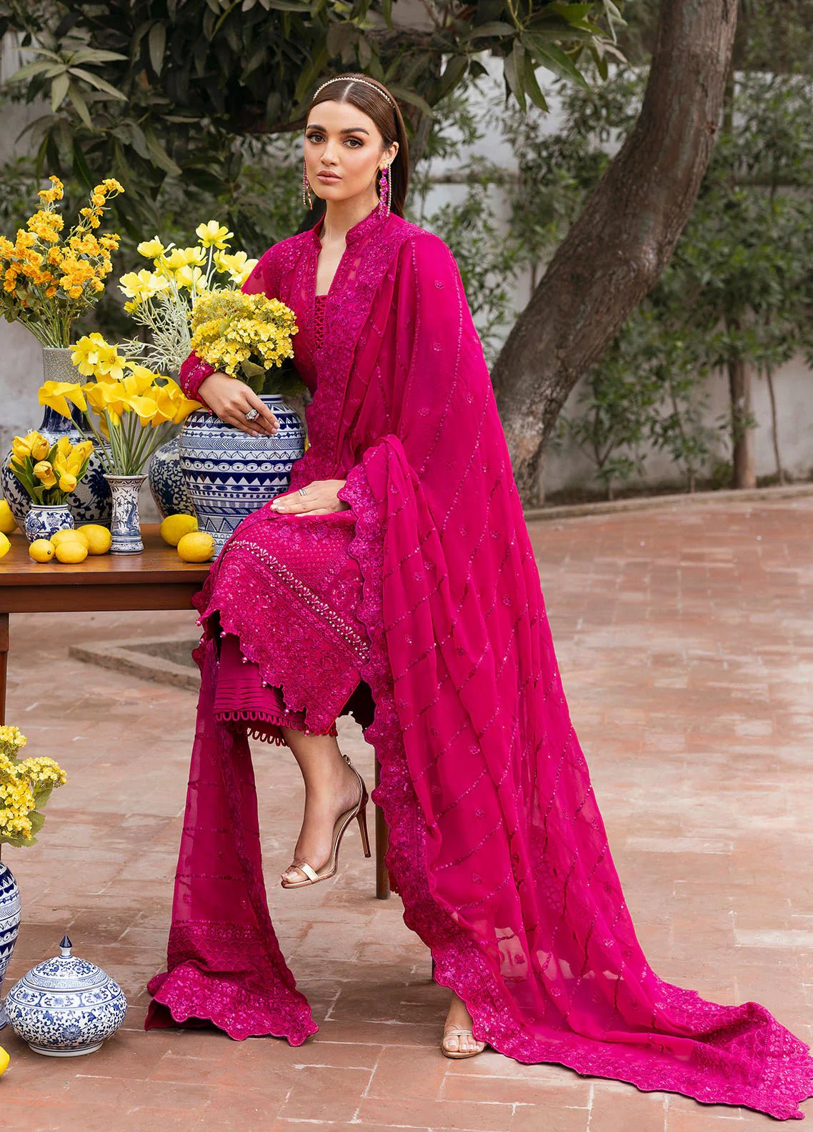 Model wearing Gulaal Zevira hot pink embroidered chiffon dress with matching dupatta and trousers. Shop Pakistani clothes online in the UK now.