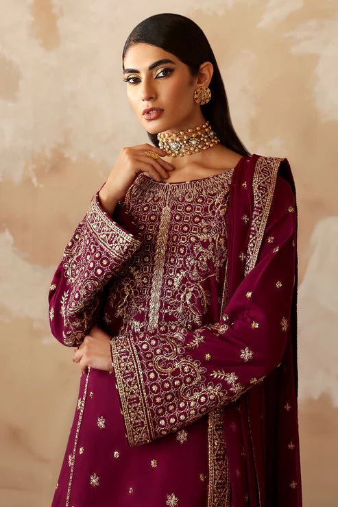 Model wearing a stunning deep maroon Shehrnaaz Raw Silk outfit by Gulaal. This festive ensemble features intricate embroidery and sequins on silk, paired with an embroidered chiffon dupatta and silk trousers, perfect for elegant occasions.