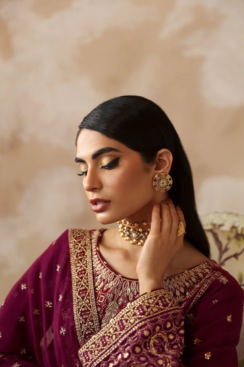 Model wearing a stunning deep maroon Shehrnaaz Raw Silk outfit by Gulaal. This festive ensemble features intricate embroidery and sequins on silk, paired with an embroidered chiffon dupatta and silk trousers, perfect for elegant occasions.