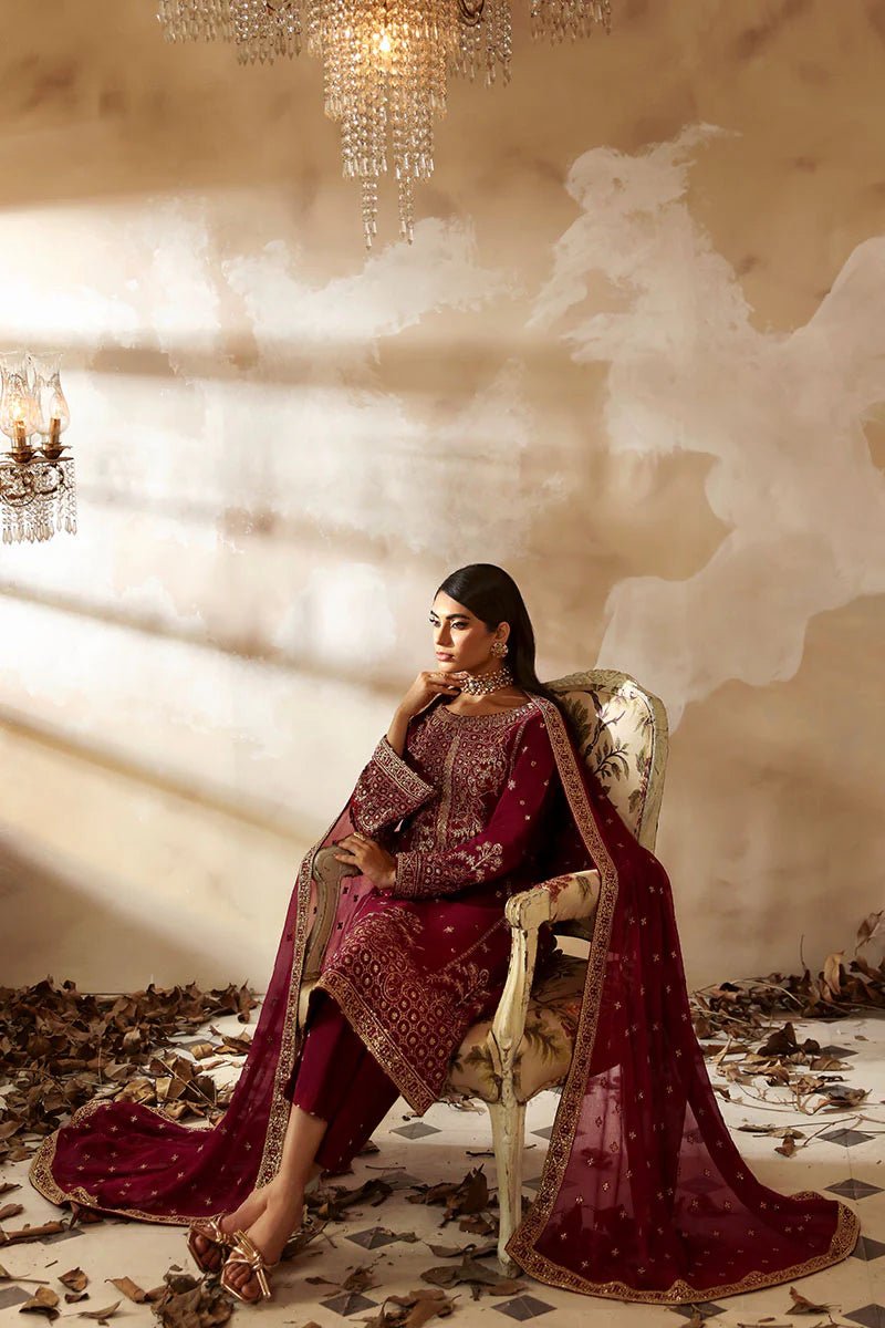 Model wearing a stunning deep maroon Shehrnaaz Raw Silk outfit by Gulaal. This festive ensemble features intricate embroidery and sequins on silk, paired with an embroidered chiffon dupatta and silk trousers, perfect for elegant occasions.