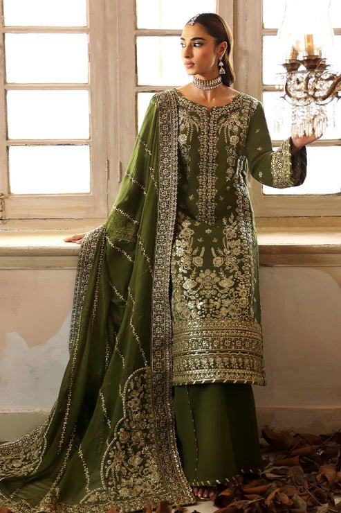 Model wearing an olive - green Gulaal Shehrnaaz Raw Silk outfit, embellished with intricate embroidery and sequins on the front, sleeves, and back. The look is completed with a fully embroidered chiffon dupatta and dyed silk trousers, ideal for festive occasions.