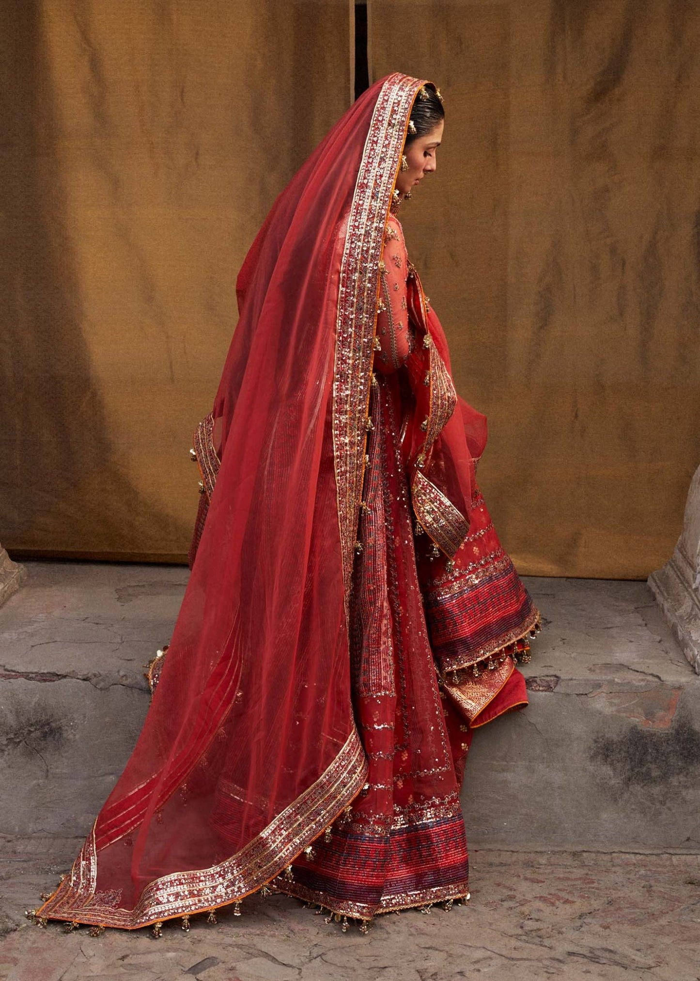 Model wearing red Bulori dress from Hussain Rehar Luxury Festive FW/24, featuring intricate embroidery and embellishments. Pakistani clothes online in the UK.