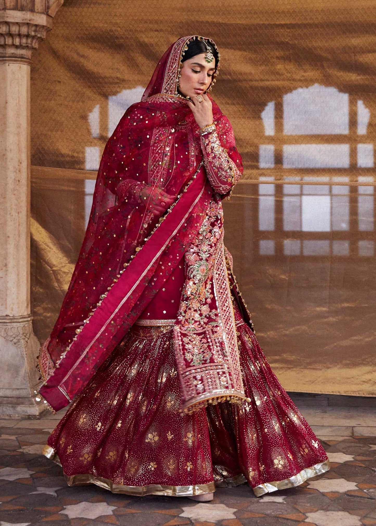 Model wearing red Gulal dress from Hussain Rehar Luxury Festive FW/24, featuring intricate embroidery. Pakistani clothes online UK.