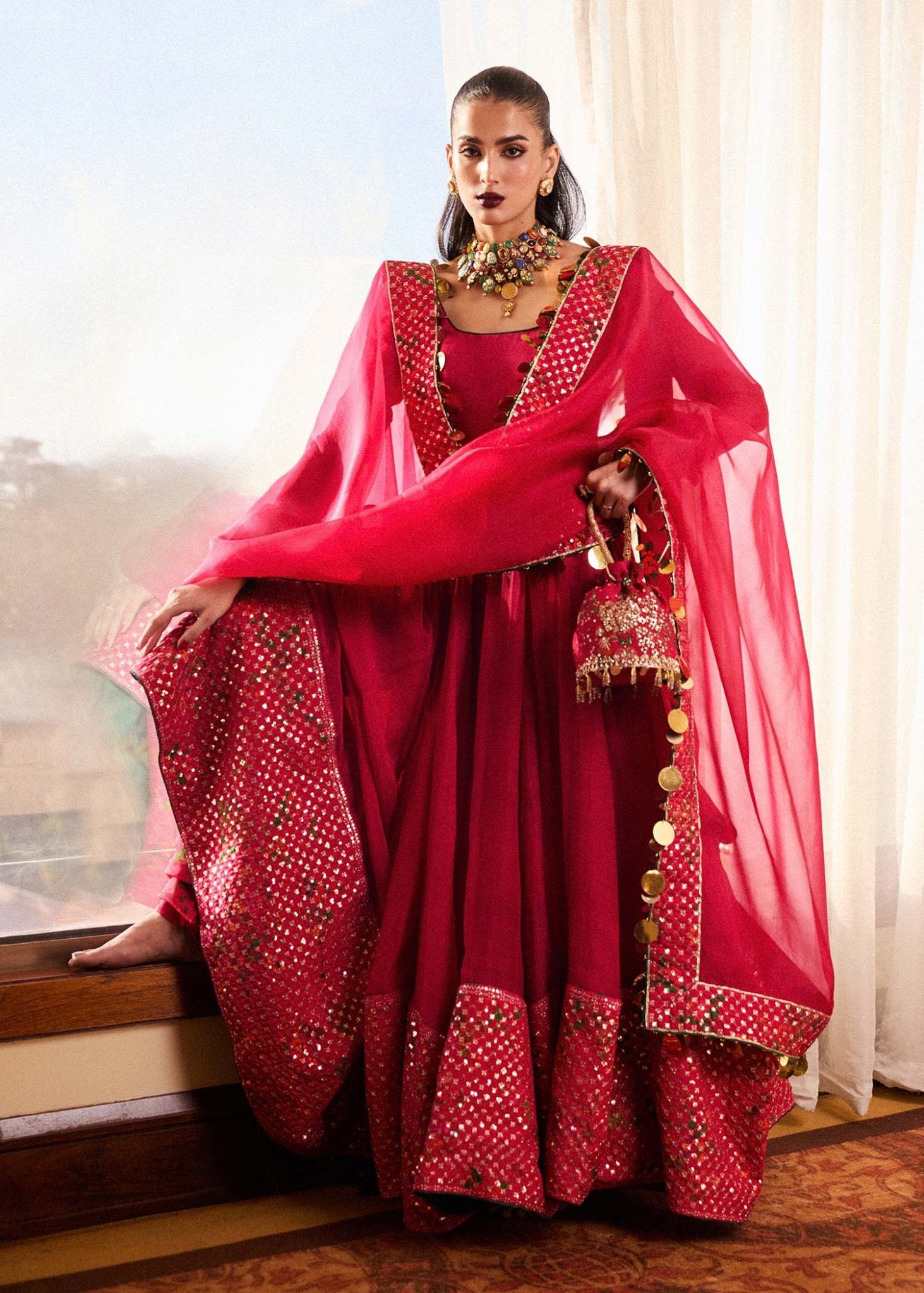 Model wearing Hussain Rehar Roshan dress in vibrant red, embellished with gold accents, perfect for Eid and Pakistani lawn suits in the UK.