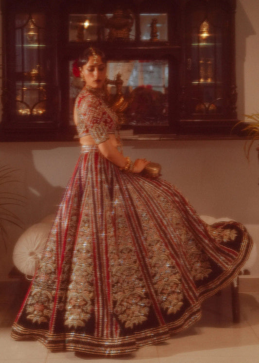 Hussain Rehar's Mushq bridal ensemble from Rehar Nagar Bridals'24, featuring intricate red and gold embellishments on a red base, ideal for luxury bridal wear. Available online in the UK for formal Pakistani bridal attire.