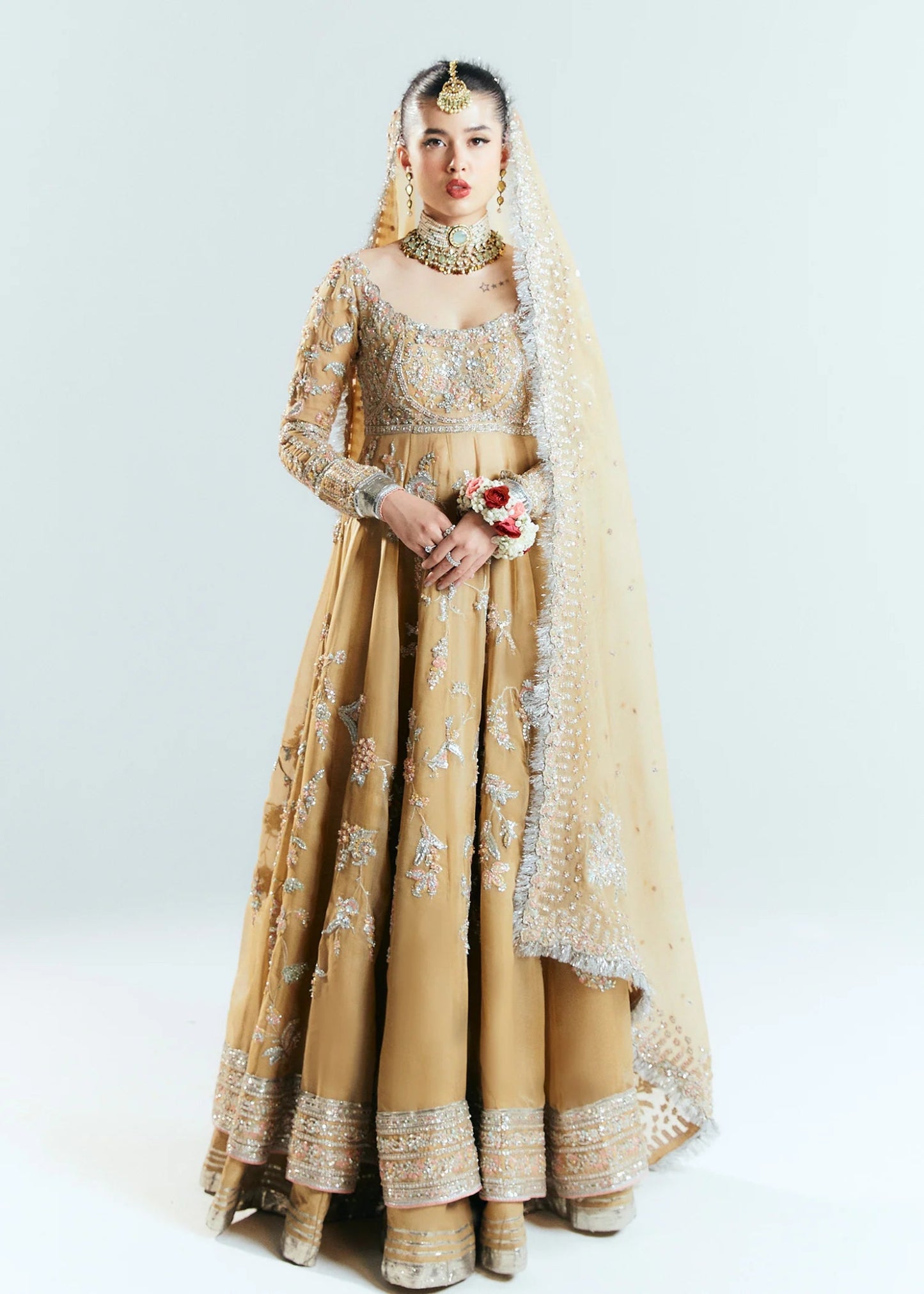 Model wearing a golden Hussain Rehar Aether dress from the Sitaray Formals collection, embellished with intricate silver embroidery.