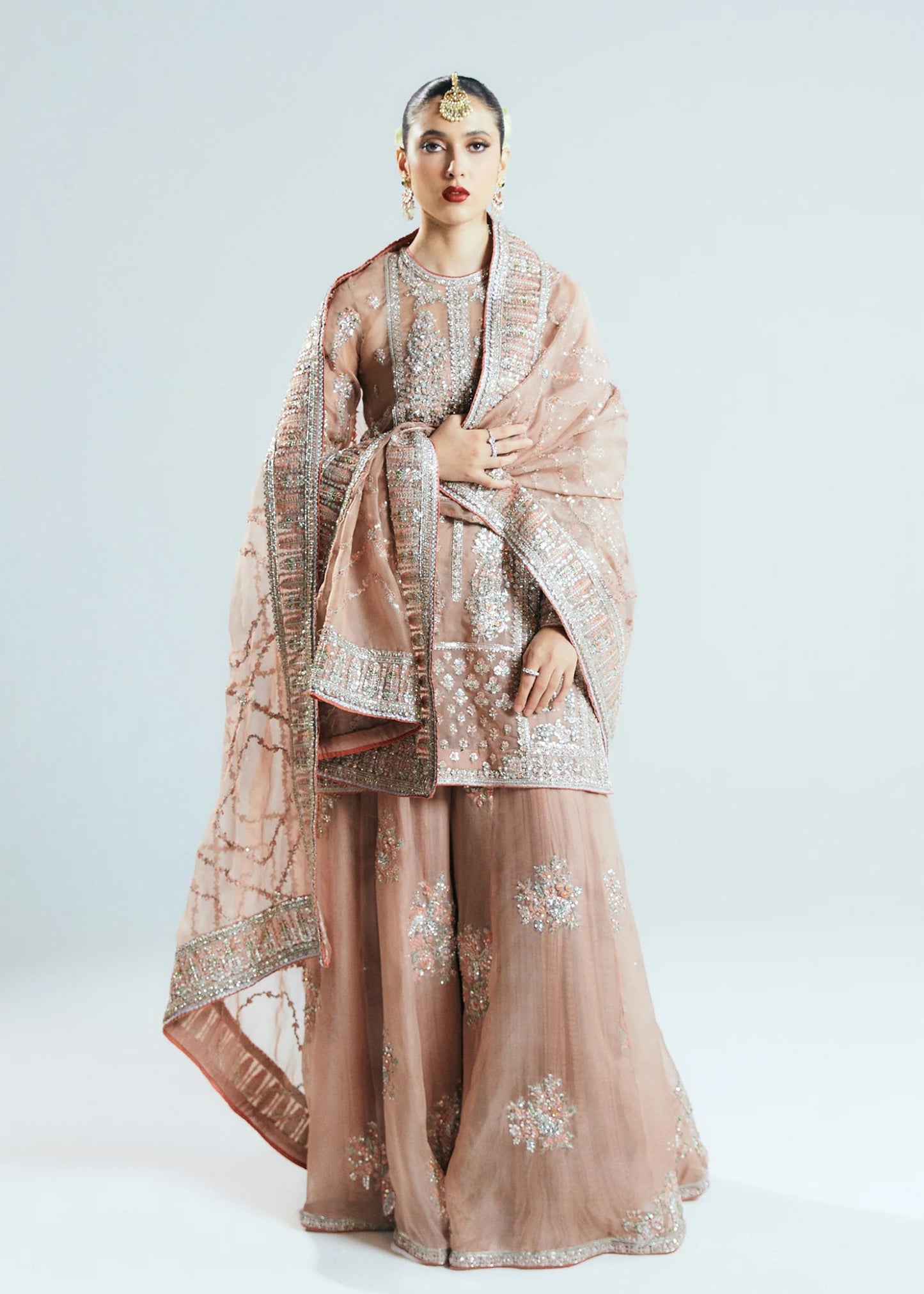 Model wearing a beige Dune dress from Hussain Rehar's Sitaray Formals collection. The dress features intricate embroidery and embellishments, perfect for wedding attire. Available for Pakistani clothes online in the UK.