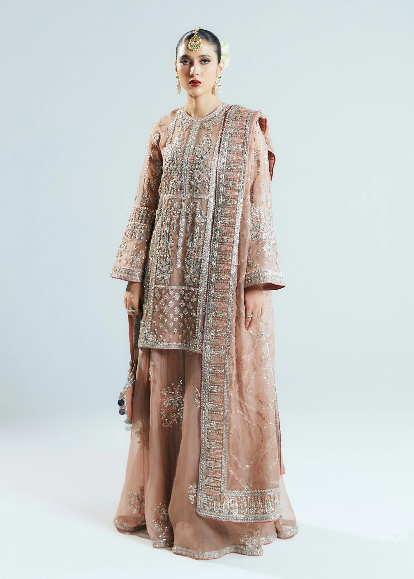 Model wearing a beige Dune dress from Hussain Rehar's Sitaray Formals collection. The dress features intricate embroidery and embellishments, perfect for wedding attire. Available for Pakistani clothes online in the UK.