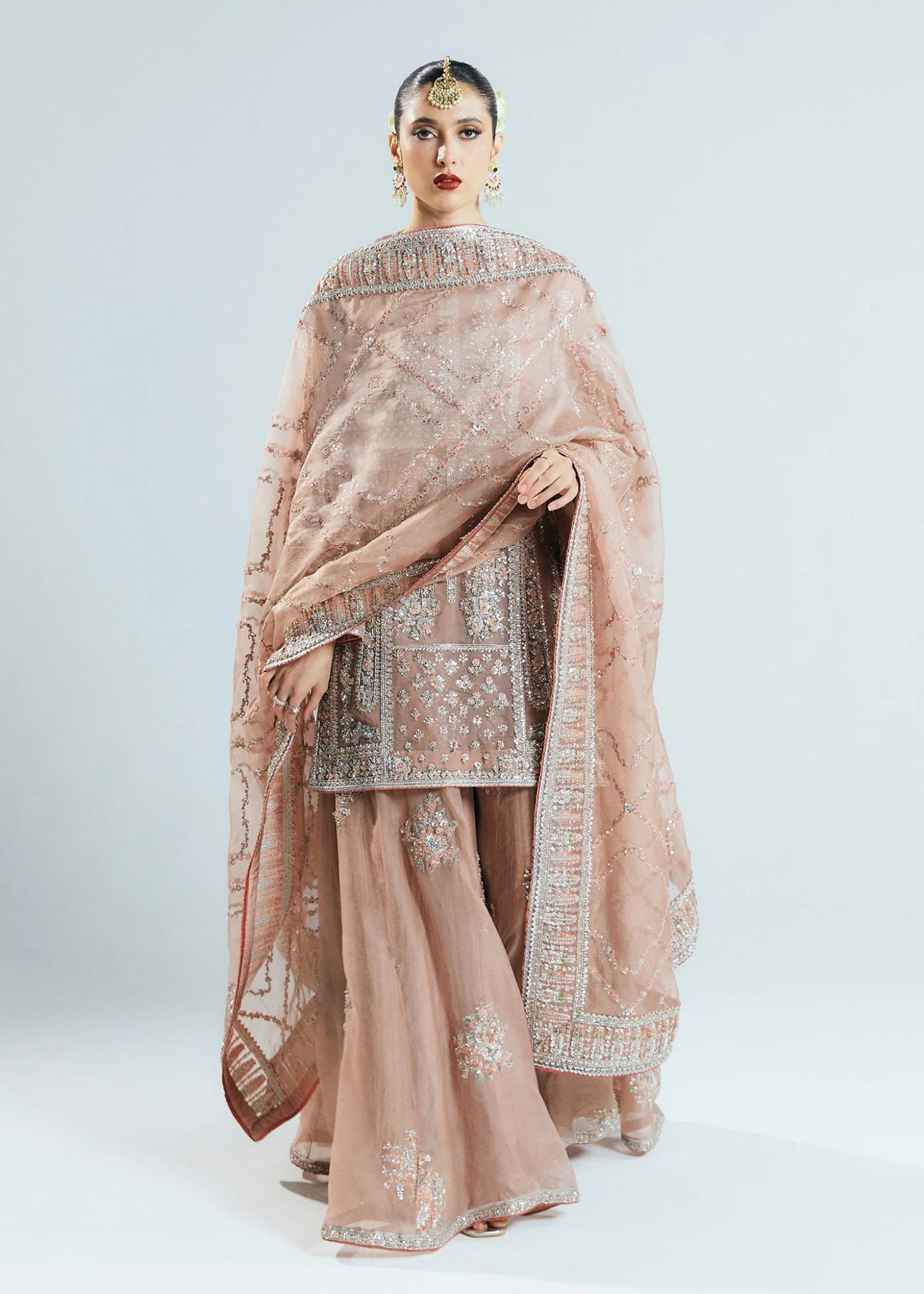 Model wearing a beige Dune dress from Hussain Rehar's Sitaray Formals collection. The dress features intricate embroidery and embellishments, perfect for wedding attire. Available for Pakistani clothes online in the UK.