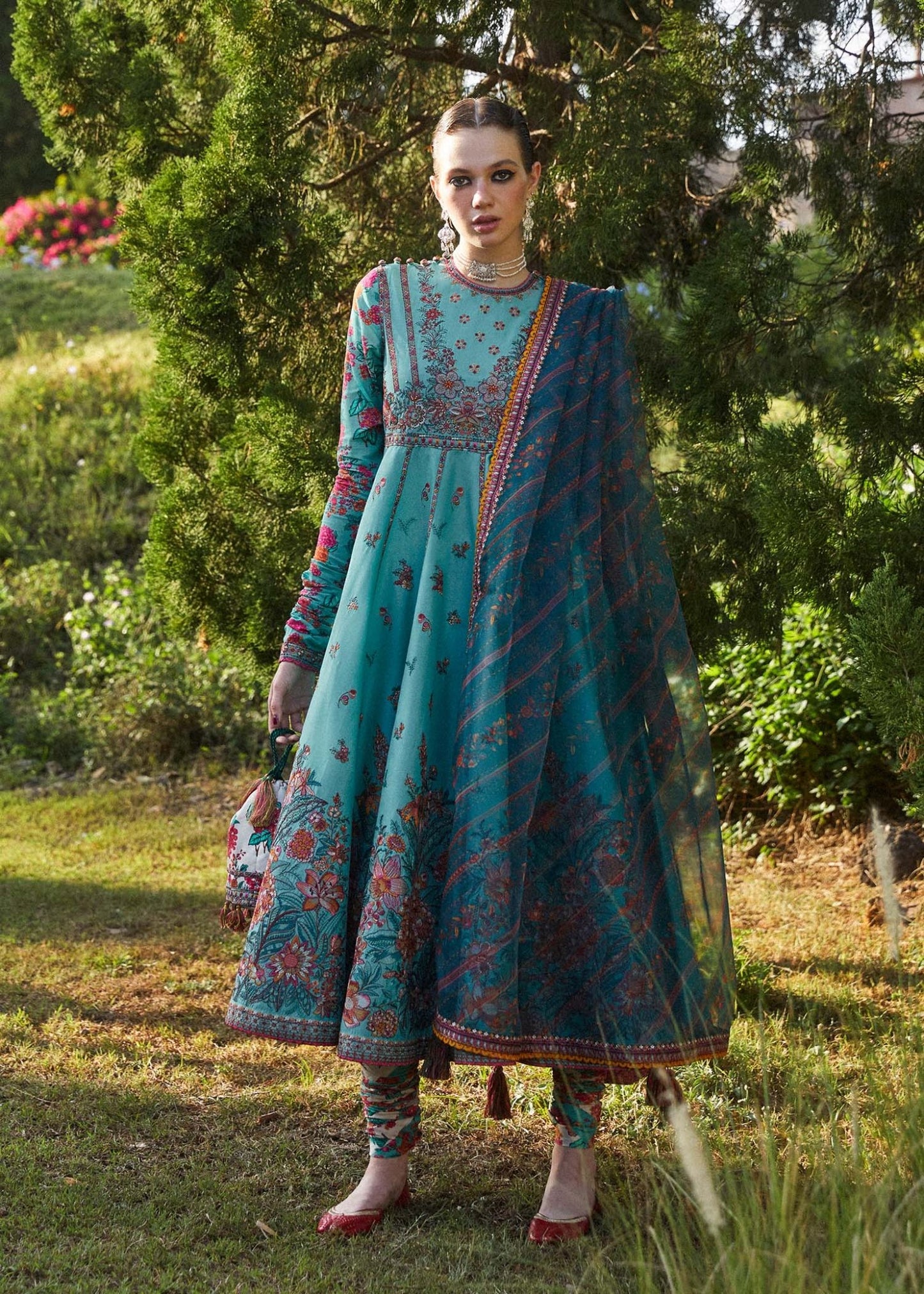 Model in Hussain Rehar Jheel dress, teal with intricate patterns, epitomizes elegant Pakistani clothes UK.