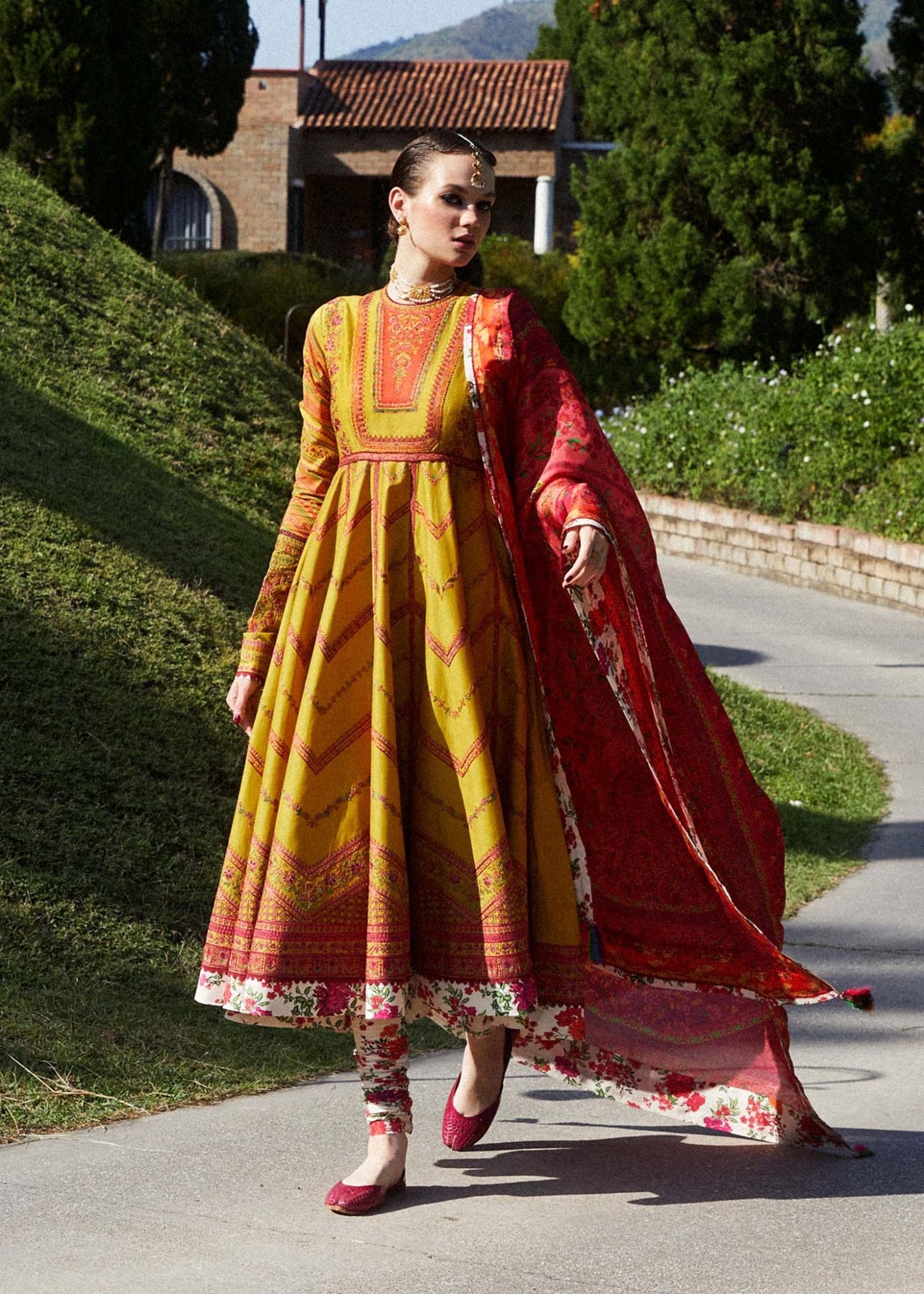 Model in Hussain Rehar Sunehri dress, vibrant yellow with red details, embodying Pakistani fashion UK.