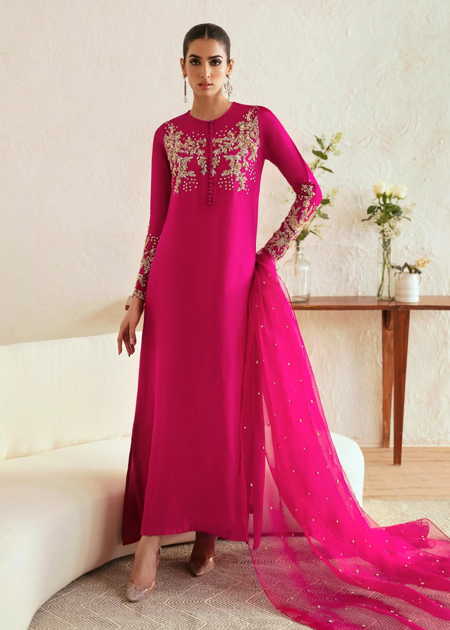 Model wearing a bright pink Myra dress from Kanwal Malik, featuring intricate golden embroidery on the bodice and sleeves. Pakistani clothes online in UK, wedding clothes.