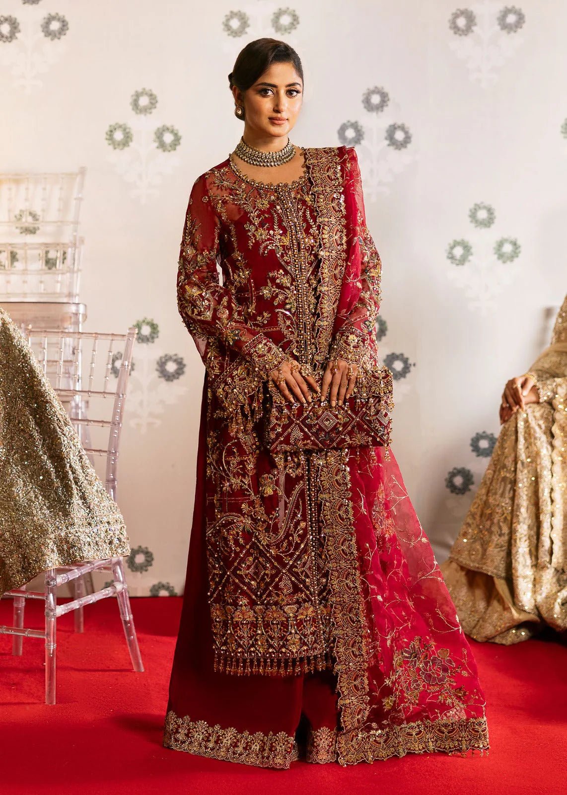 Model wearing Kanwal Malik Maahi Wedding Festive '24 ARMALA, a deep red ensemble with intricate gold embroidery, ideal for wedding celebrations. Available for Pakistani clothes online in the UK.