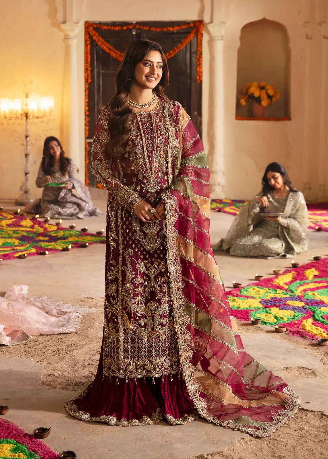 Model wearing Kanwal Malik Maahi Wedding Festive '24 FALAK, a deep maroon ensemble with intricate gold embellishments, perfect for weddings. Available for Pakistani clothes online in the UK.