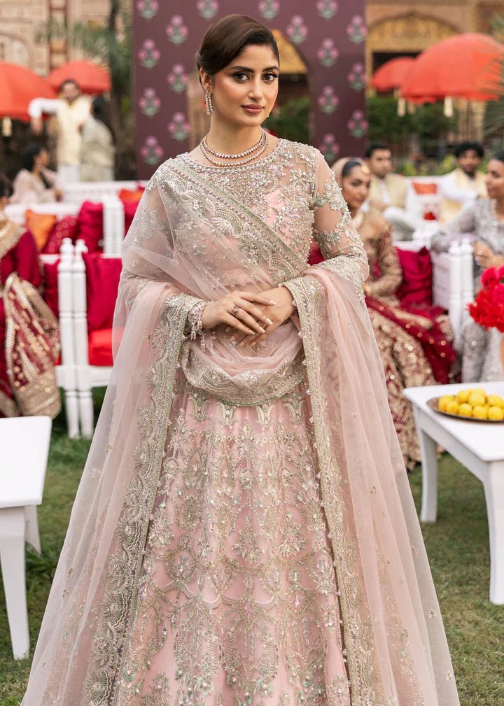 Model wearing Kanwal Malik Maahi Wedding Festive '24 NAGEEN, a soft pink bridal dress with intricate silver embellishments, ideal for weddings. Available for Pakistani clothes online in the UK.