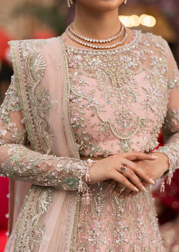 Model wearing Kanwal Malik Maahi Wedding Festive '24 NAGEEN, a soft pink bridal dress with intricate silver embellishments, ideal for weddings. Available for Pakistani clothes online in the UK.