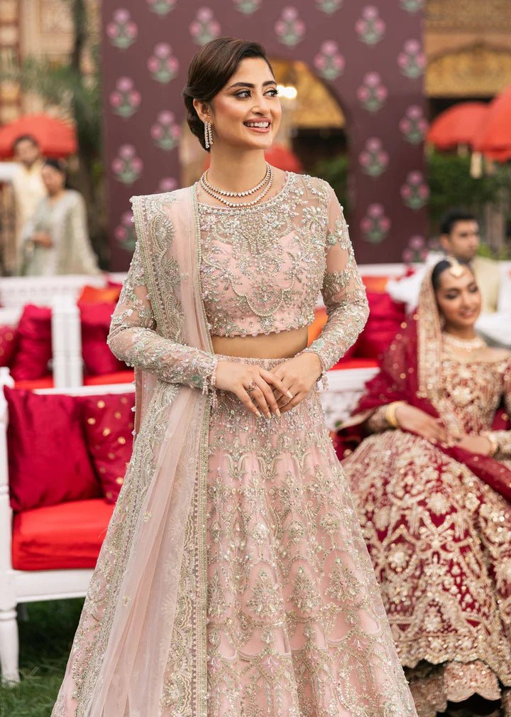 Model wearing Kanwal Malik Maahi Wedding Festive '24 NAGEEN, a soft pink bridal dress with intricate silver embellishments, ideal for weddings. Available for Pakistani clothes online in the UK.