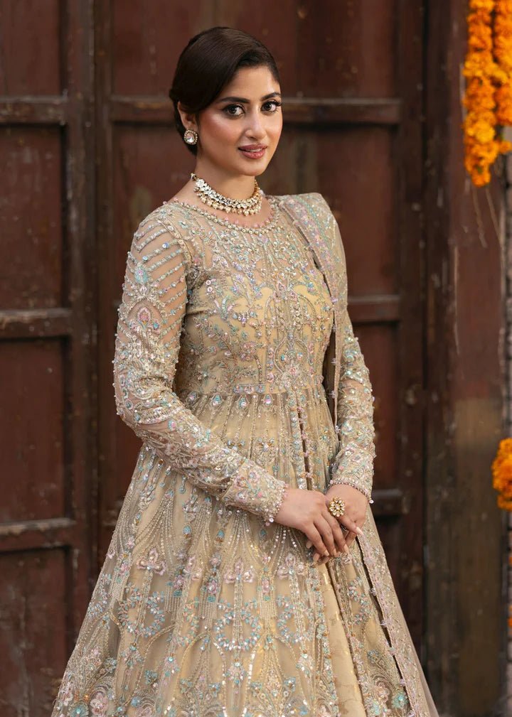 Model wearing Kanwal Malik Maahi Wedding Festive '24 ZOFIA, a luxurious champagne - colored bridal dress adorned with intricate embellishments, perfect for weddings. Available for Pakistani clothes online in the UK.