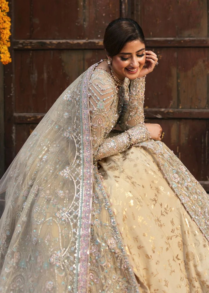 Model wearing Kanwal Malik Maahi Wedding Festive '24 ZOFIA, a luxurious champagne - colored bridal dress adorned with intricate embellishments, perfect for weddings. Available for Pakistani clothes online in the UK.