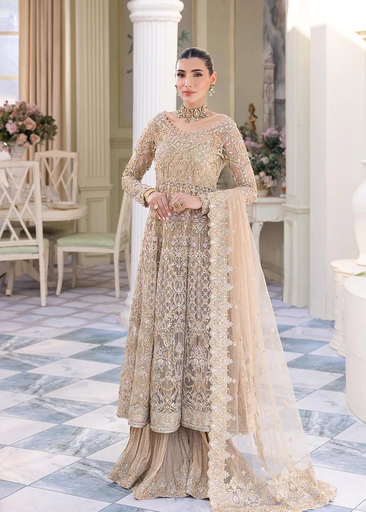 Model wearing Kanwal Malik Nia dress, gold with ornate embellishments, luxurious Pakistani attire UK.