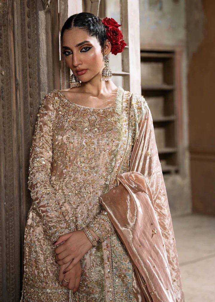 Model wearing a champagne - colored Meeram dress from Kanwal Malik's Sajni II Formal Collection, featuring intricate embroidery and velvet shawl. Pakistani wedding clothes available online in the UK.