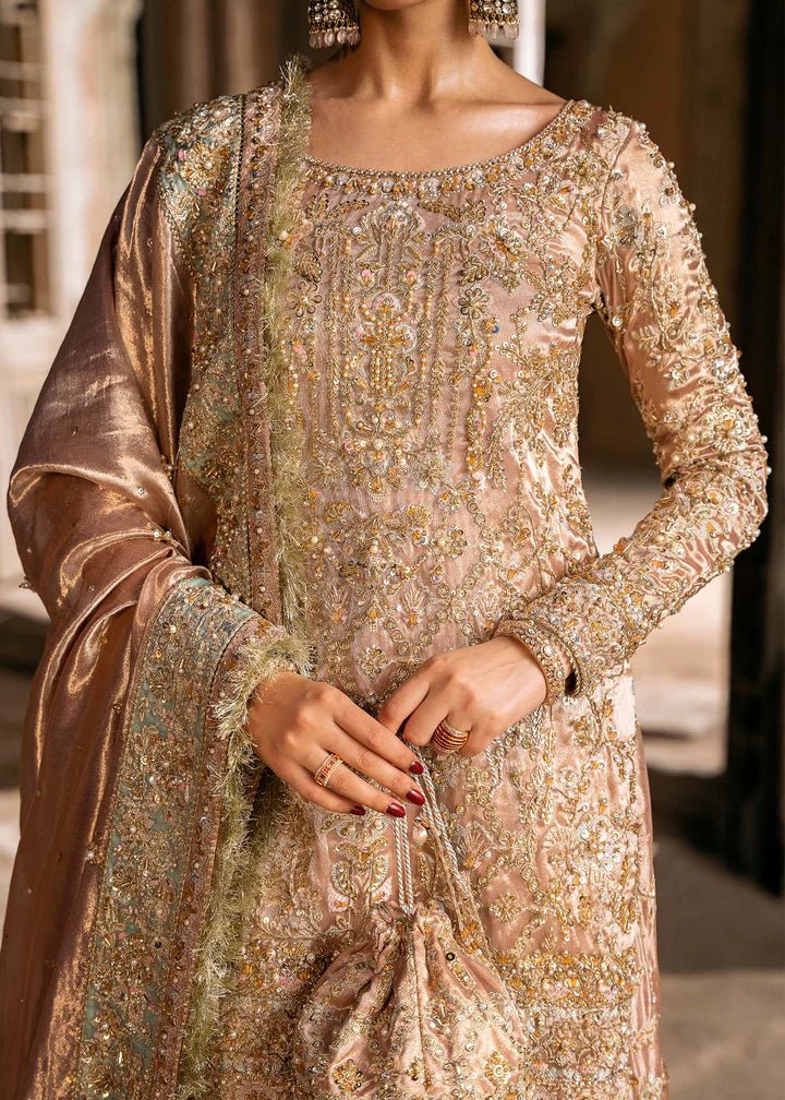 Model wearing a champagne - colored Meeram dress from Kanwal Malik's Sajni II Formal Collection, featuring intricate embroidery and velvet shawl. Pakistani wedding clothes available online in the UK.