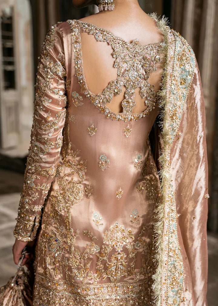 Model wearing a champagne - colored Meeram dress from Kanwal Malik's Sajni II Formal Collection, featuring intricate embroidery and velvet shawl. Pakistani wedding clothes available online in the UK.