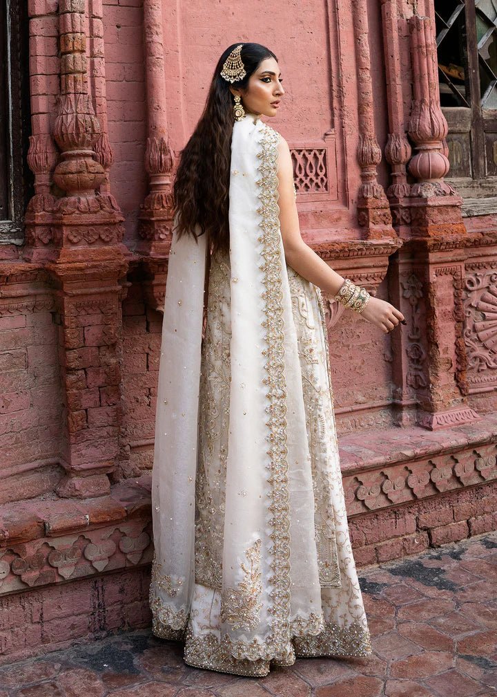 Model wearing an ivory Nisha dress from Kanwal Malik's Sajni II Formal Collection, detailed with intricate gold embroidery and paired with a matching dupatta. Pakistani wedding clothes available online in the UK.