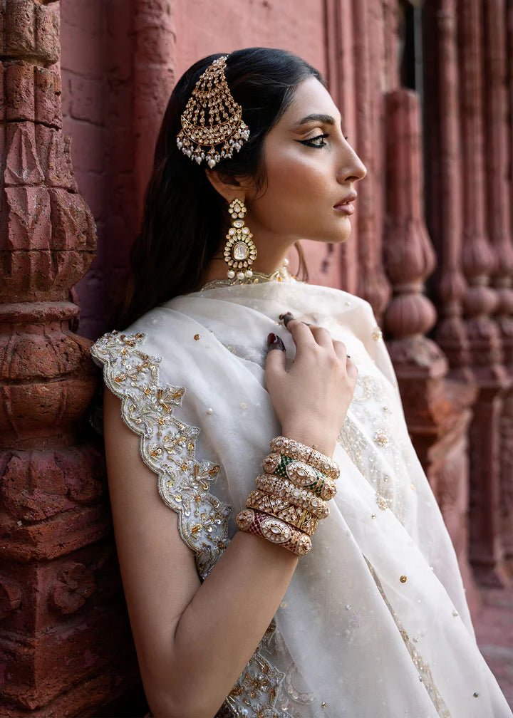 Model wearing an ivory Nisha dress from Kanwal Malik's Sajni II Formal Collection, detailed with intricate gold embroidery and paired with a matching dupatta. Pakistani wedding clothes available online in the UK.