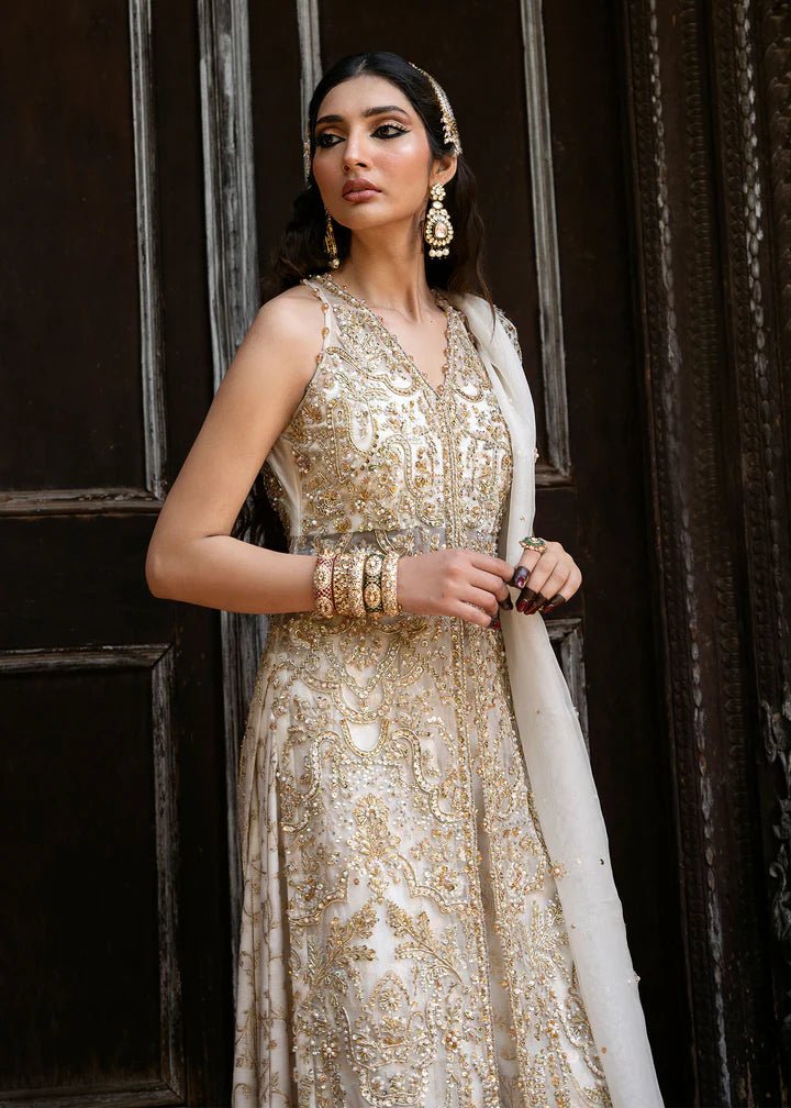 Model wearing an ivory Nisha dress from Kanwal Malik's Sajni II Formal Collection, detailed with intricate gold embroidery and paired with a matching dupatta. Pakistani wedding clothes available online in the UK.