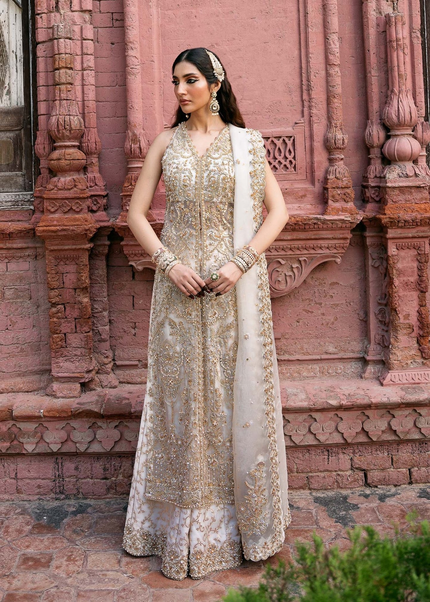 Model wearing an ivory Nisha dress from Kanwal Malik's Sajni II Formal Collection, detailed with intricate gold embroidery and paired with a matching dupatta. Pakistani wedding clothes available online in the UK.