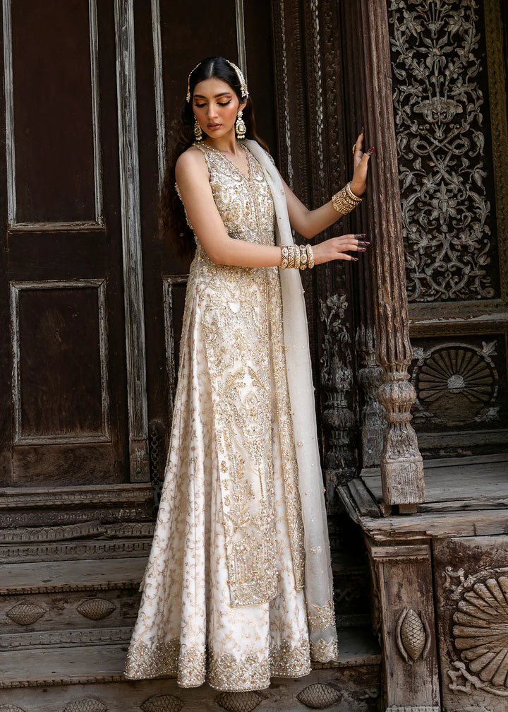 Model wearing an ivory Nisha dress from Kanwal Malik's Sajni II Formal Collection, detailed with intricate gold embroidery and paired with a matching dupatta. Pakistani wedding clothes available online in the UK.