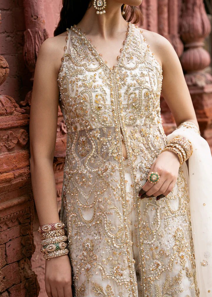 Model wearing an ivory Nisha dress from Kanwal Malik's Sajni II Formal Collection, detailed with intricate gold embroidery and paired with a matching dupatta. Pakistani wedding clothes available online in the UK.