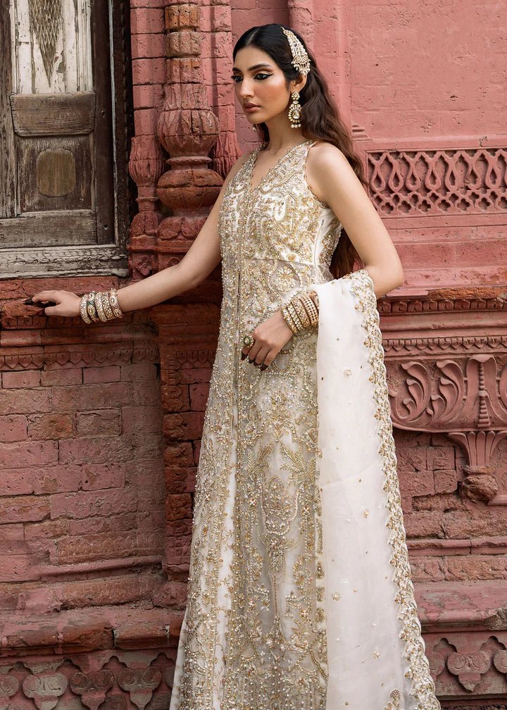 Model wearing an ivory Nisha dress from Kanwal Malik's Sajni II Formal Collection, detailed with intricate gold embroidery and paired with a matching dupatta. Pakistani wedding clothes available online in the UK.