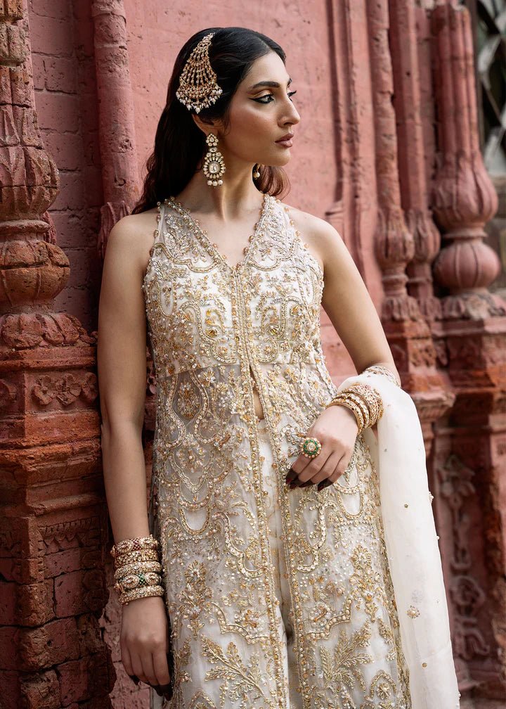 Model wearing an ivory Nisha dress from Kanwal Malik's Sajni II Formal Collection, detailed with intricate gold embroidery and paired with a matching dupatta. Pakistani wedding clothes available online in the UK.