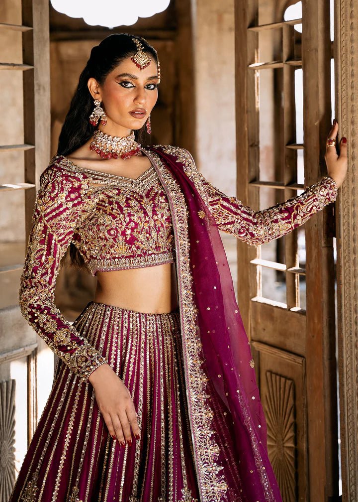 Model wearing a deep magenta and gold embellished Raina lehenga from Kanwal Malik's Sajni II collection. Pakistani wedding clothes online in the UK.