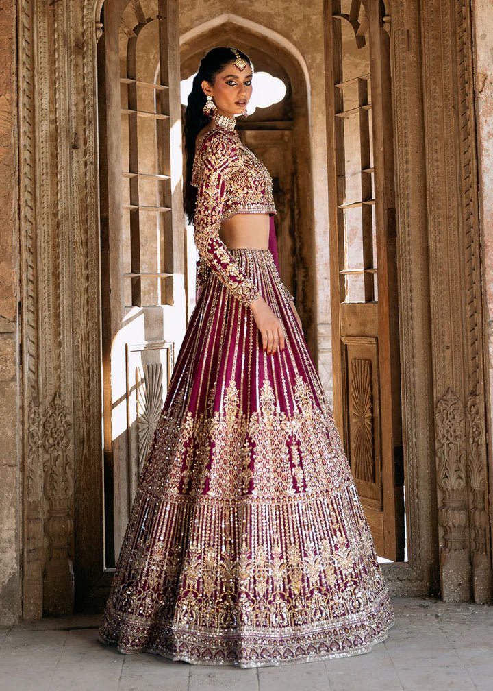 Model wearing a deep magenta and gold embellished Raina lehenga from Kanwal Malik's Sajni II collection. Pakistani wedding clothes online in the UK.