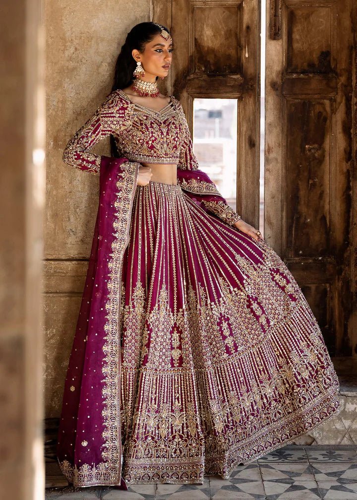 Model wearing a deep magenta and gold embellished Raina lehenga from Kanwal Malik's Sajni II collection. Pakistani wedding clothes online in the UK.