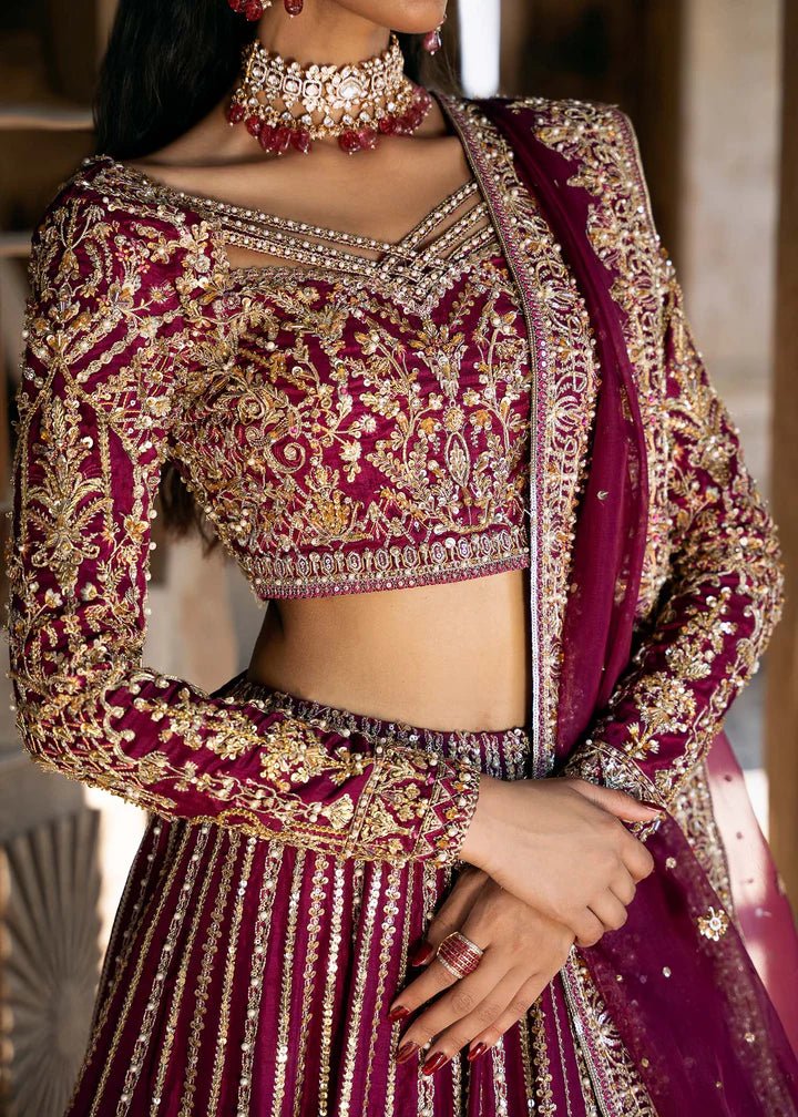 Model wearing a deep magenta and gold embellished Raina lehenga from Kanwal Malik's Sajni II collection. Pakistani wedding clothes online in the UK.