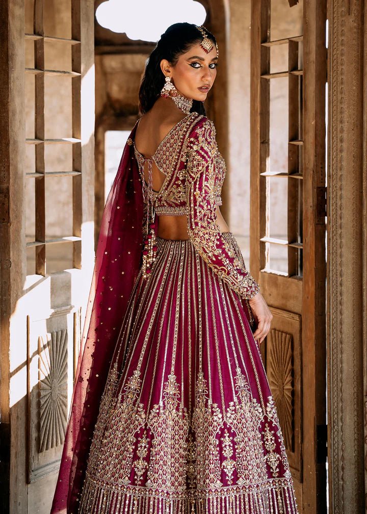 Model wearing a deep magenta and gold embellished Raina lehenga from Kanwal Malik's Sajni II collection. Pakistani wedding clothes online in the UK.