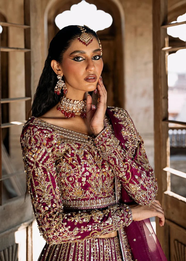 Model wearing a deep magenta and gold embellished Raina lehenga from Kanwal Malik's Sajni II collection. Pakistani wedding clothes online in the UK.