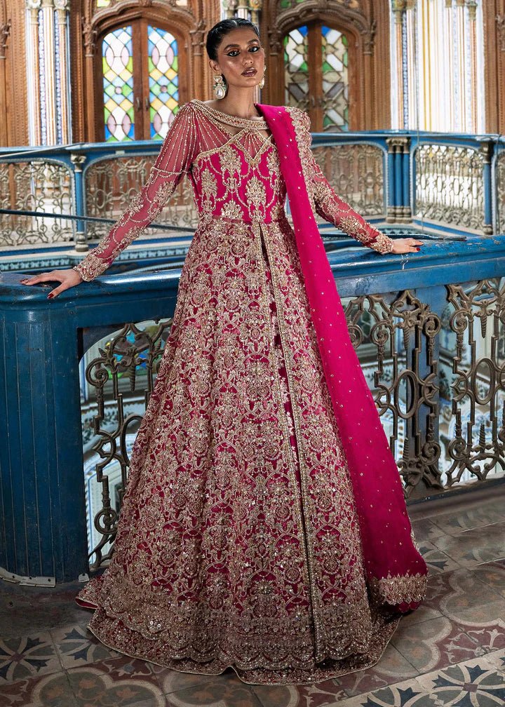 Model wearing a vibrant pink Sarosh dress from Kanwal Malik's Sajni II Formal Collection, adorned with intricate gold embroidery, paired with a matching dupatta. Pakistani wedding clothes available online in the UK.