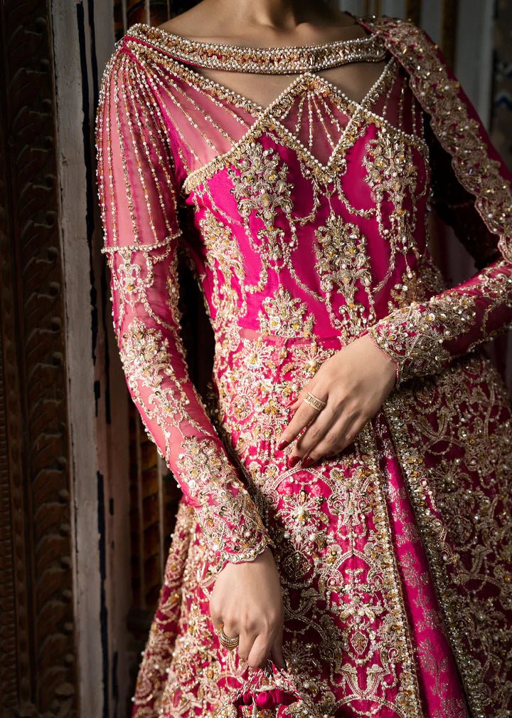 Model wearing a vibrant pink Sarosh dress from Kanwal Malik's Sajni II Formal Collection, adorned with intricate gold embroidery, paired with a matching dupatta. Pakistani wedding clothes available online in the UK.