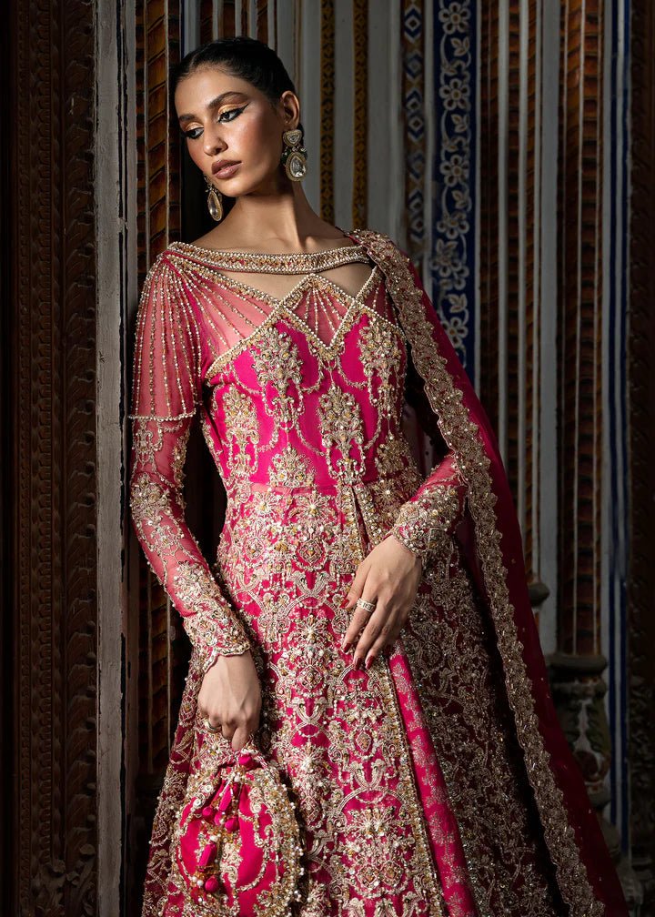 Model wearing a vibrant pink Sarosh dress from Kanwal Malik's Sajni II Formal Collection, adorned with intricate gold embroidery, paired with a matching dupatta. Pakistani wedding clothes available online in the UK.