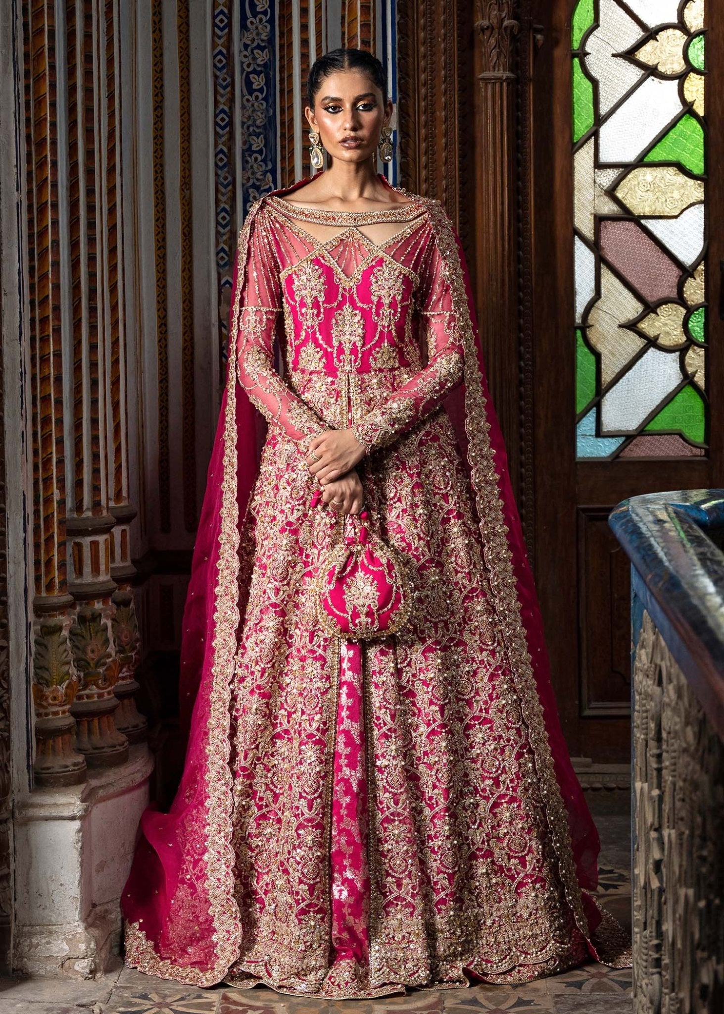 Model wearing a vibrant pink Sarosh dress from Kanwal Malik's Sajni II Formal Collection, adorned with intricate gold embroidery, paired with a matching dupatta. Pakistani wedding clothes available online in the UK.