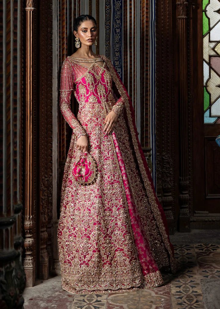 Model wearing a vibrant pink Sarosh dress from Kanwal Malik's Sajni II Formal Collection, adorned with intricate gold embroidery, paired with a matching dupatta. Pakistani wedding clothes available online in the UK.