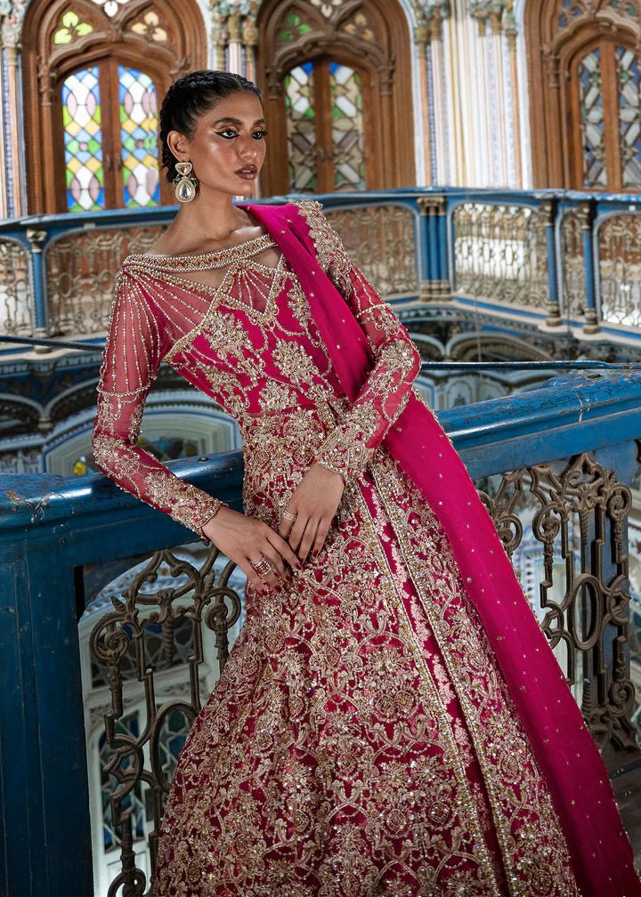 Model wearing a vibrant pink Sarosh dress from Kanwal Malik's Sajni II Formal Collection, adorned with intricate gold embroidery, paired with a matching dupatta. Pakistani wedding clothes available online in the UK.