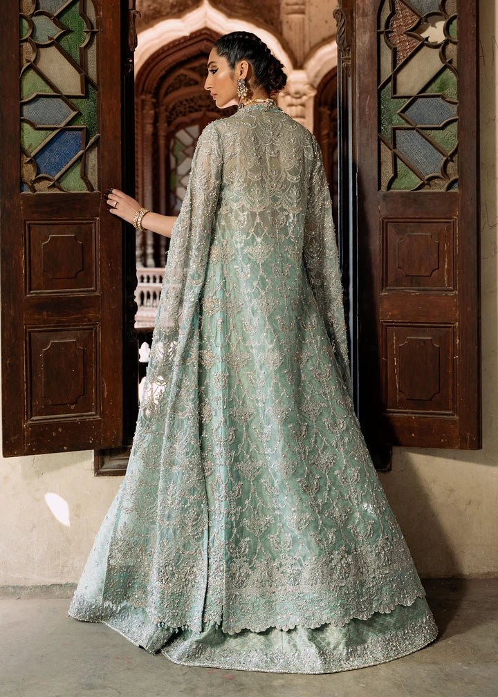 Model wearing a pastel green Shaqfaq dress from Kanwal Malik's Sajni II Formal Collection, featuring intricate embroidery and a matching cape. Pakistani wedding clothes available online in the UK.