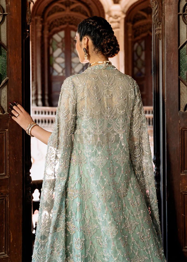 Model wearing a pastel green Shaqfaq dress from Kanwal Malik's Sajni II Formal Collection, featuring intricate embroidery and a matching cape. Pakistani wedding clothes available online in the UK.