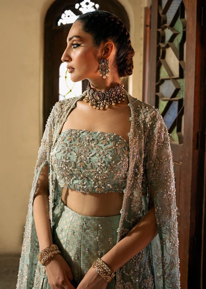 Model wearing a pastel green Shaqfaq dress from Kanwal Malik's Sajni II Formal Collection, featuring intricate embroidery and a matching cape. Pakistani wedding clothes available online in the UK.